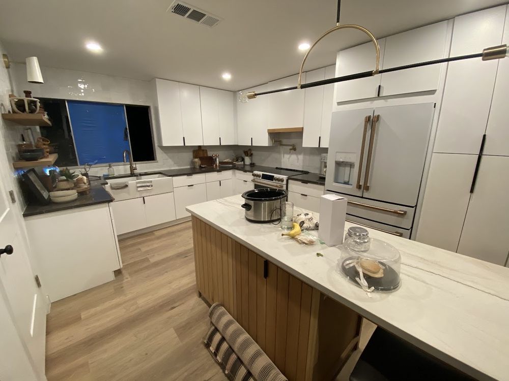 Modern white kitchen with island, wooden accents, and appliances.