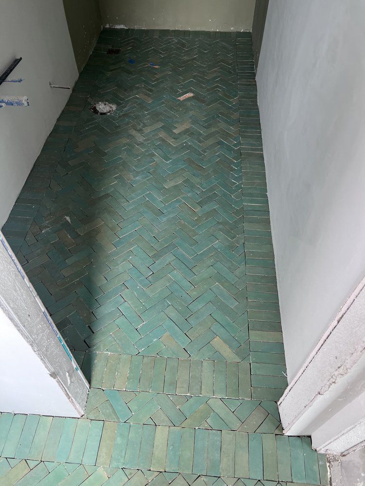 Herringbone pattern turquoise floor tiles in a hallway.
