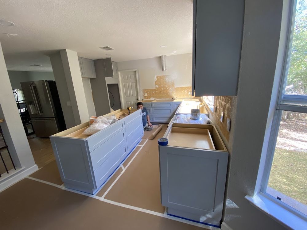 Kitchen remodel in progress: Blue cabinets, countertops, and a person working on the island.
