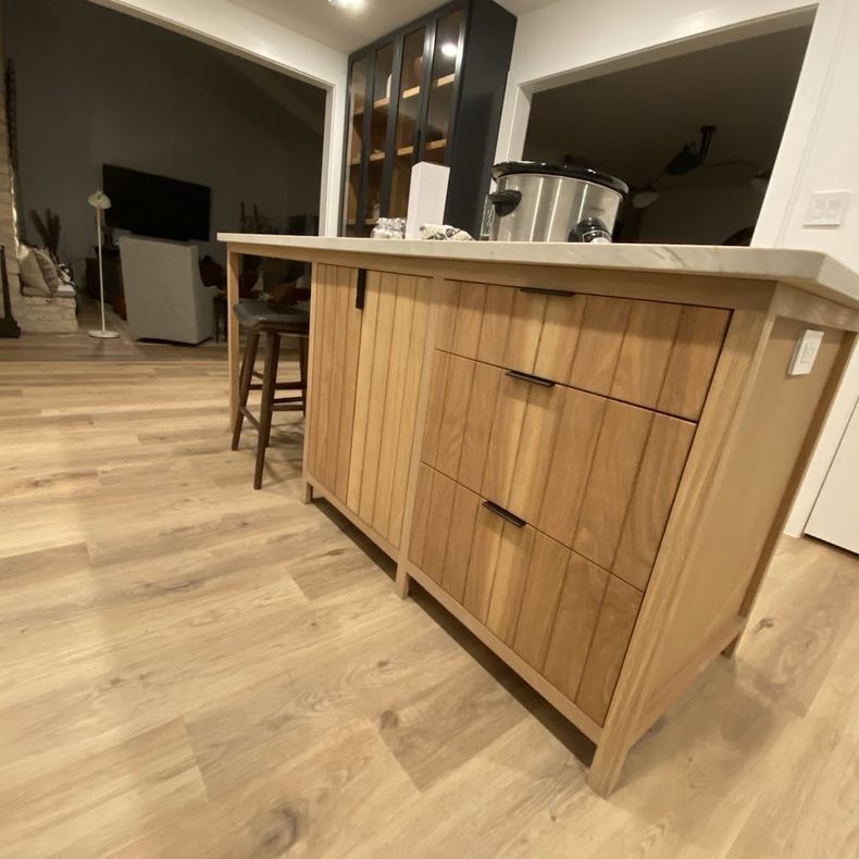 Wooden kitchen island with drawers and a countertop, in a room with light-colored flooring.