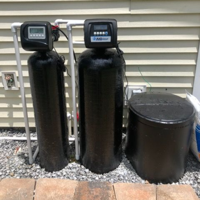 Two black water treatment tanks with digital displays, and a salt tank, outdoors.