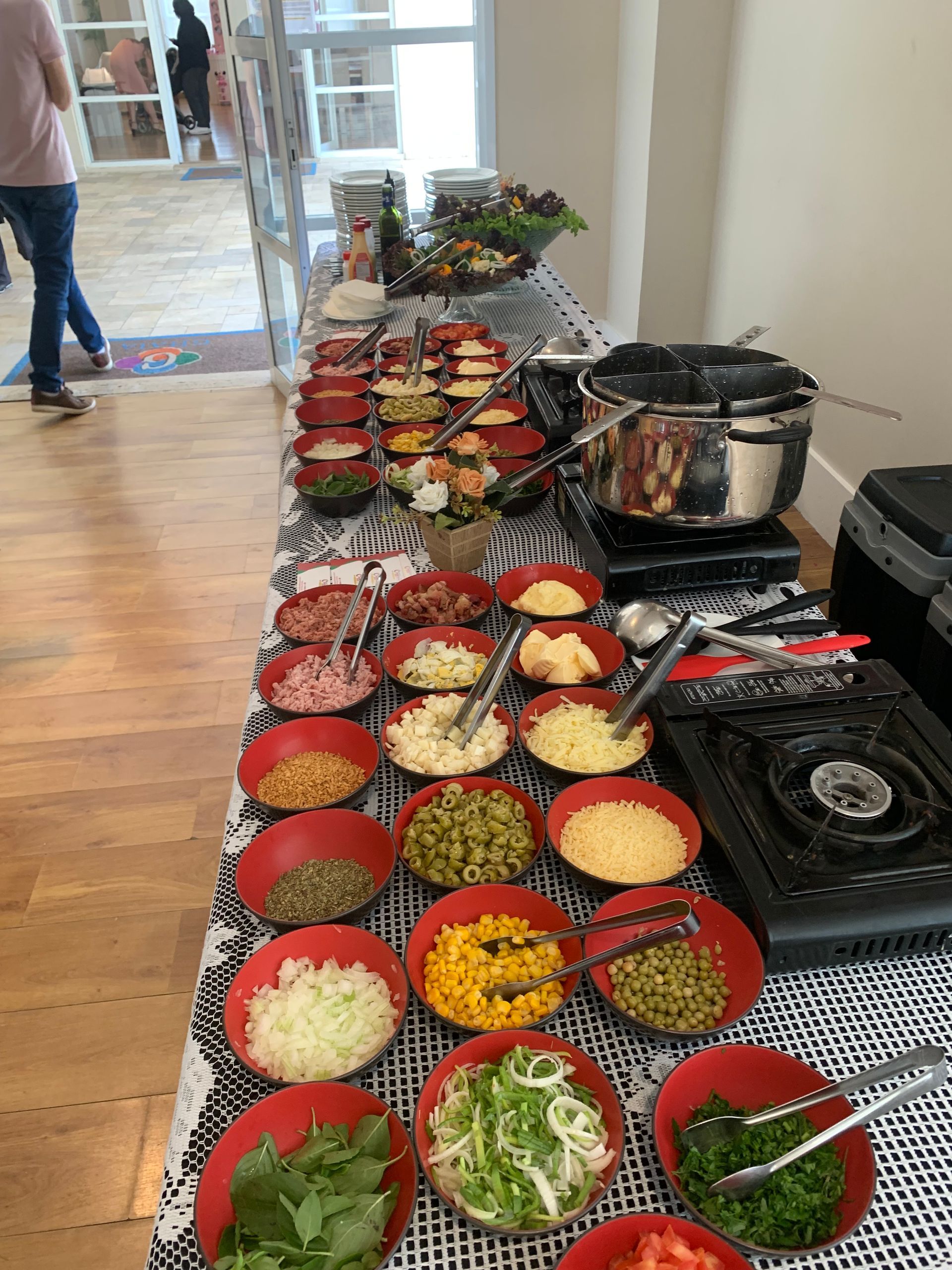 Uma mesa de bufê cheia de tigelas de comida e condimentos.