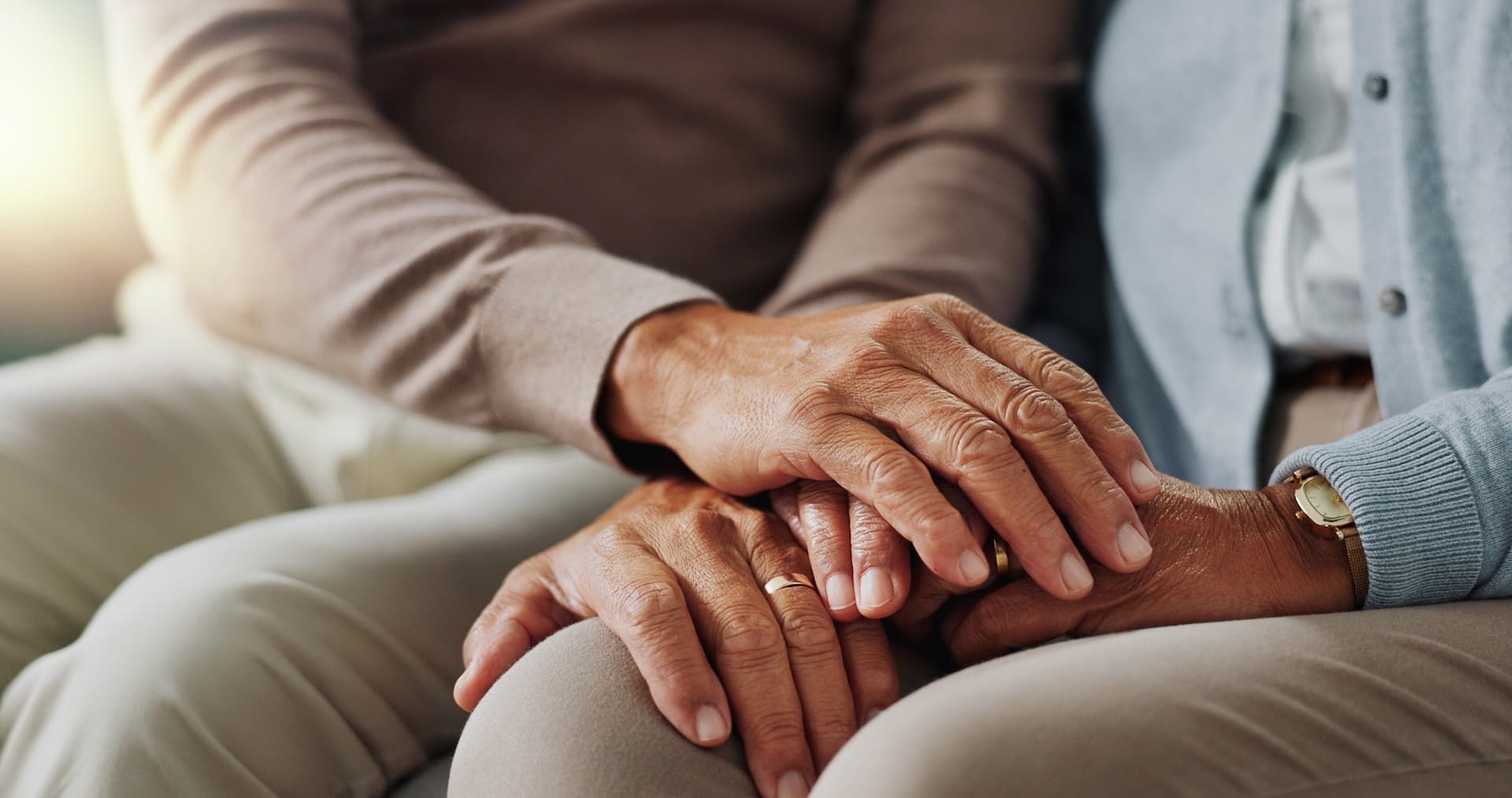 A man and a woman are holding hands against a tree trunk.