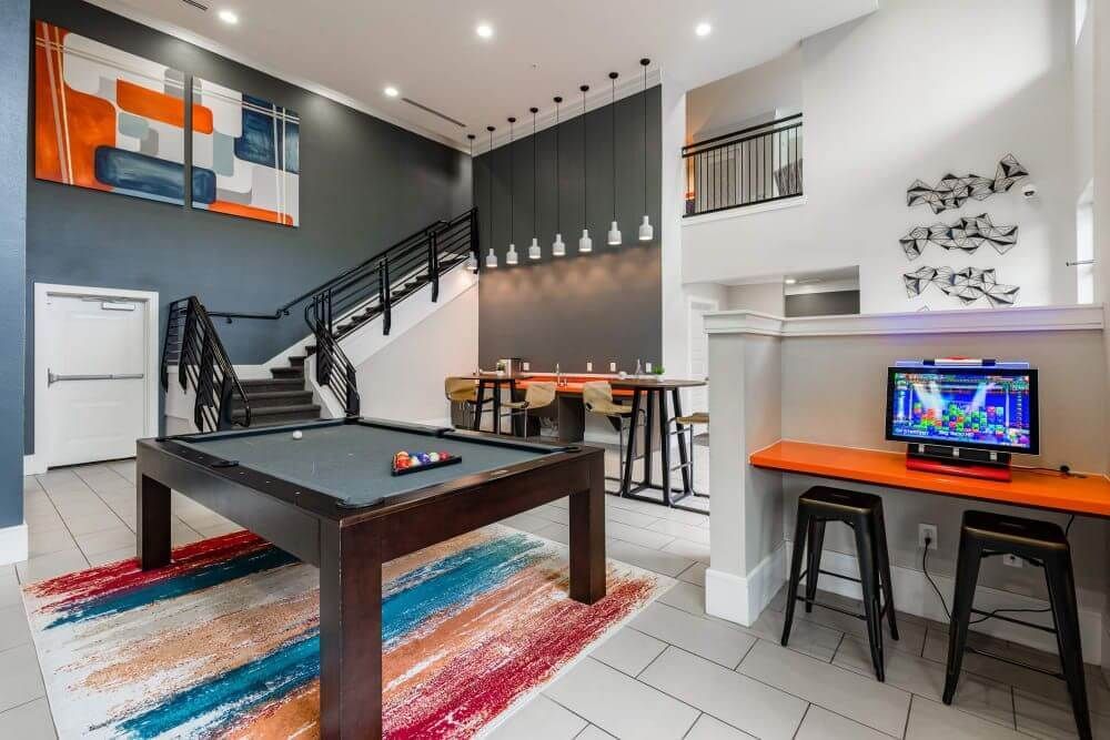 Game room with pool table, stairs, and a gaming console. Orange, gray, and white decor.