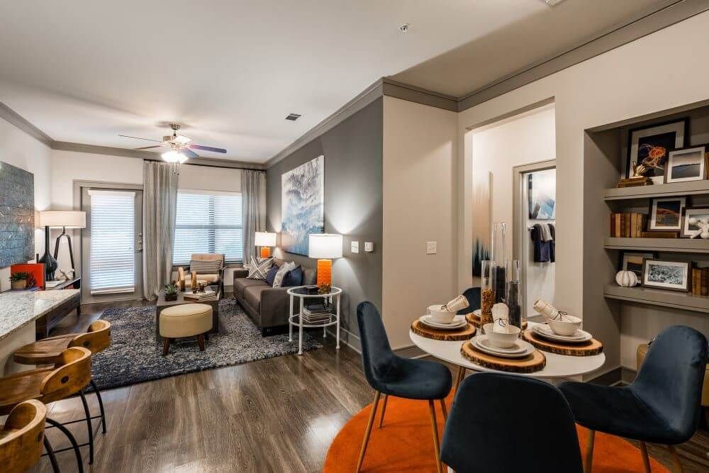 Modern apartment interior: living and dining areas, dark wood floors, blue and orange accents.