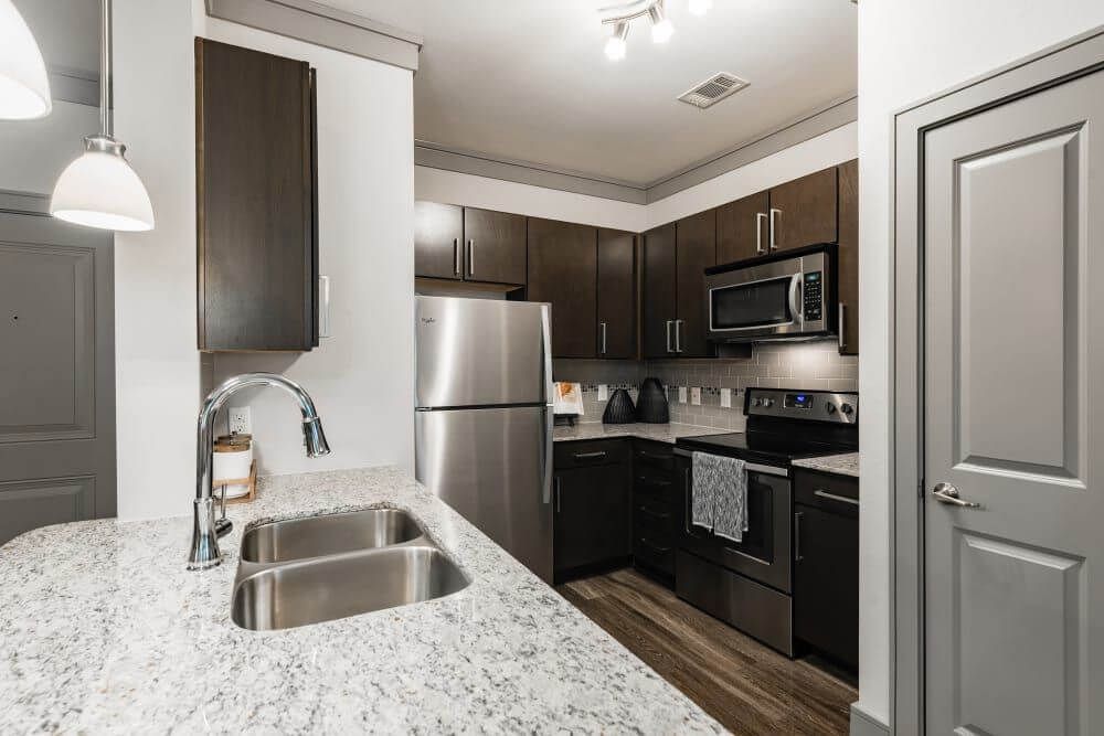 Kitchen with granite countertops, stainless steel appliances, and dark wood cabinets.