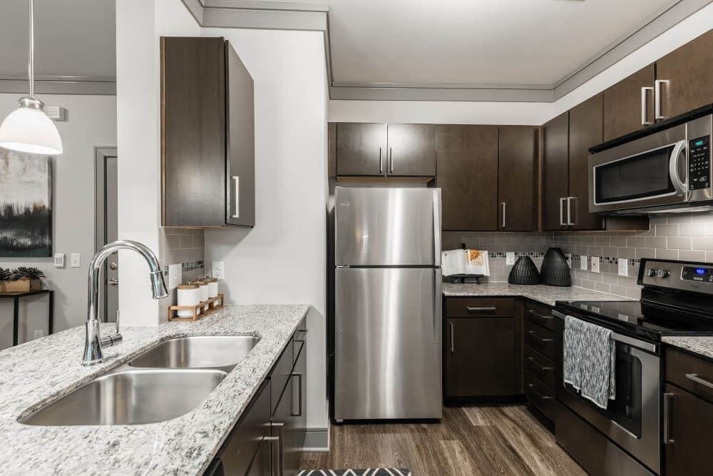 Modern kitchen with stainless steel appliances, dark cabinets, and granite countertops.