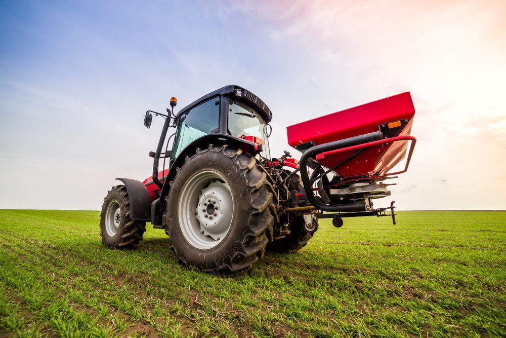 A Tractor is Spreading Fertilizer in a Field — Gloucester Rural Supplies in Gloucester, NSW