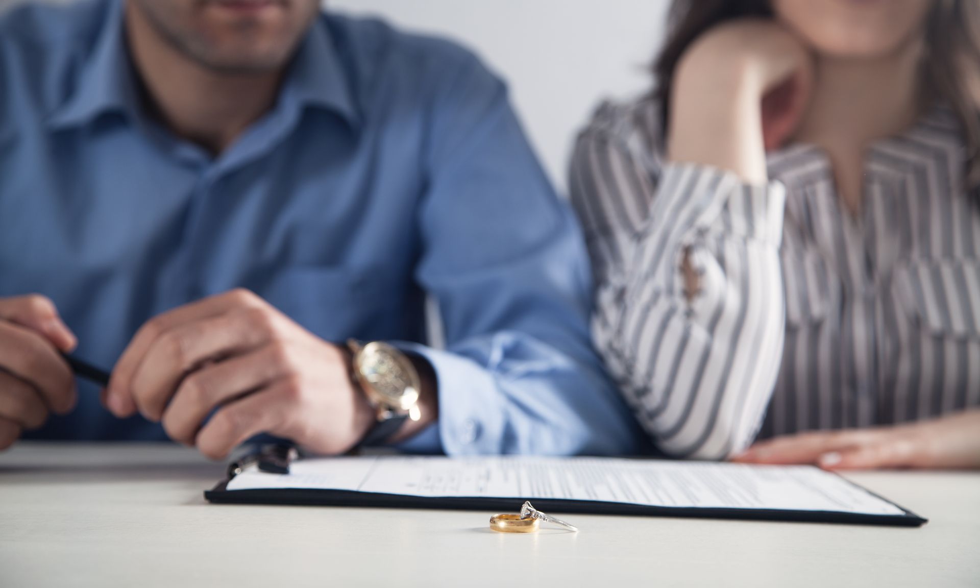 Couple with divorce contract and ring on desk.