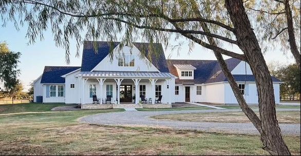 A large white house with a black roof and a driveway