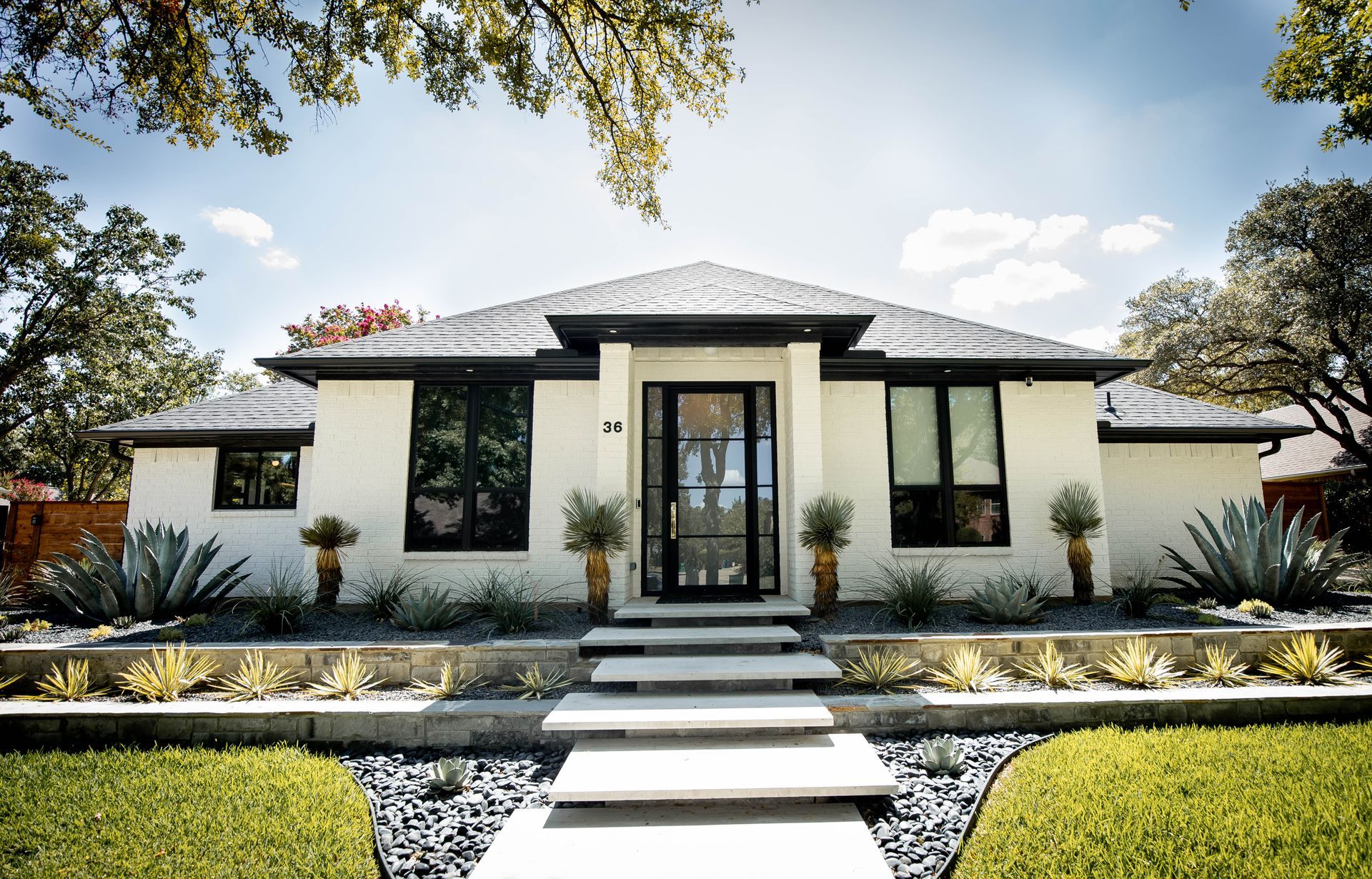 A large white house with a black roof and a driveway