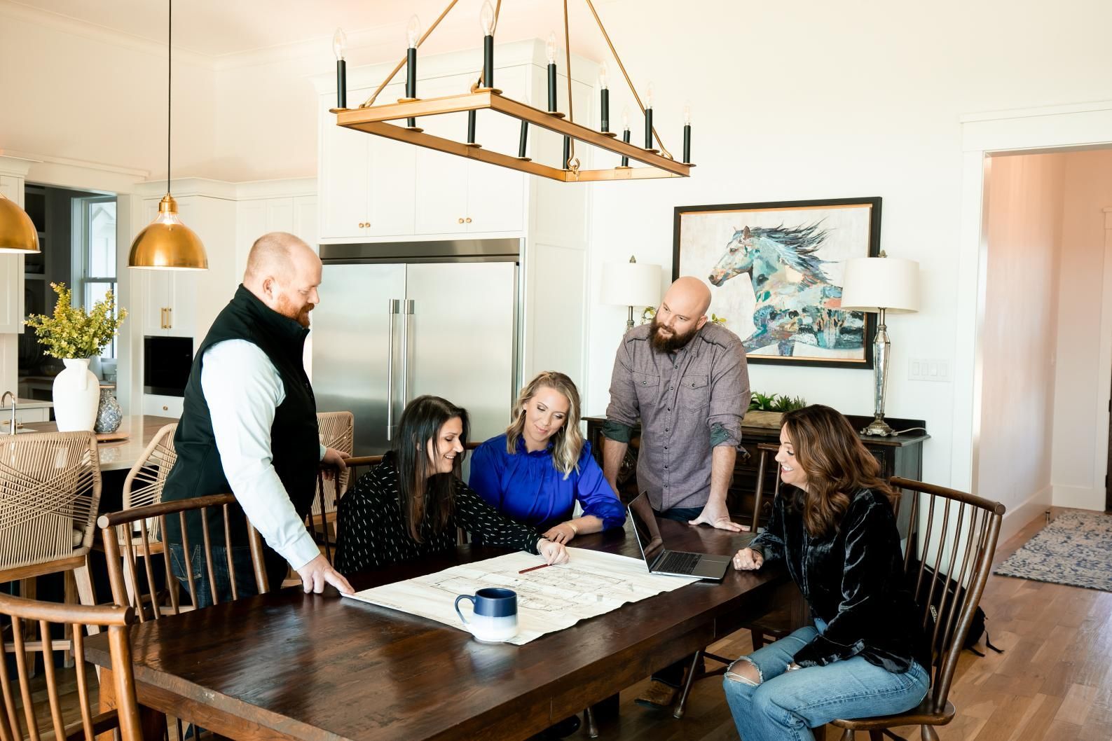 A group of people are sitting around a table looking at a blueprint.