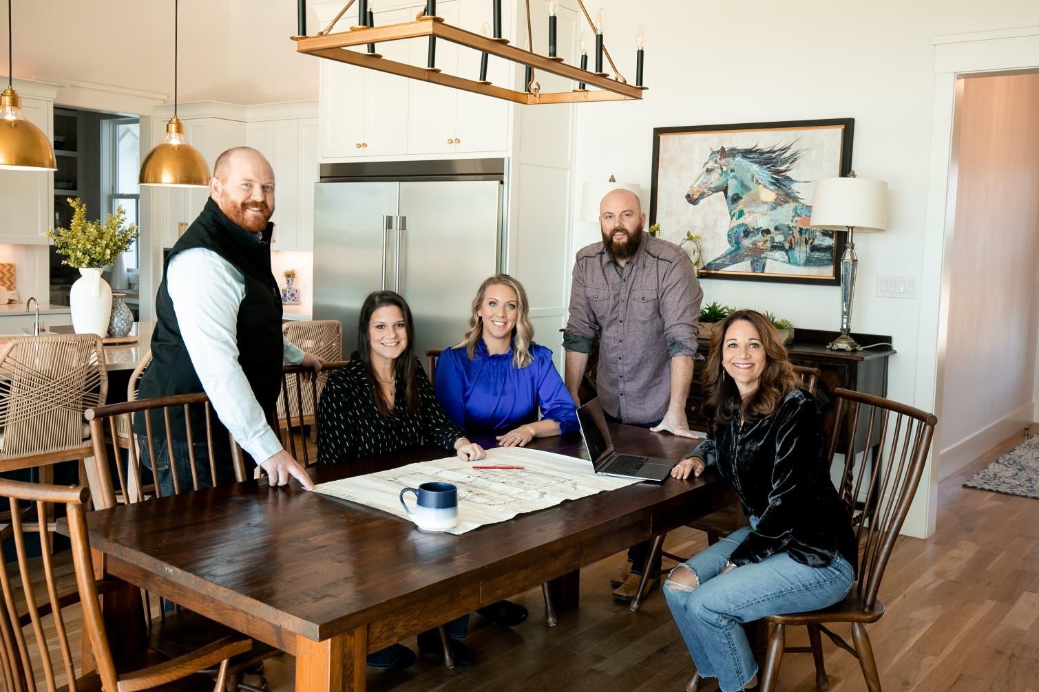 A group of people are sitting around a table in a kitchen.