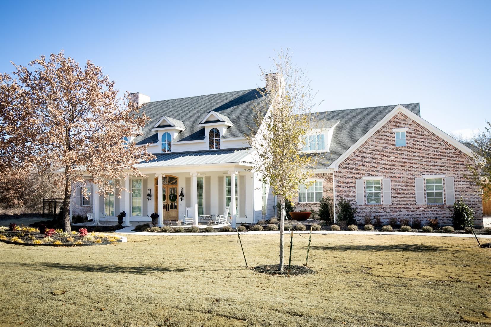 A large white house with a black roof and a driveway