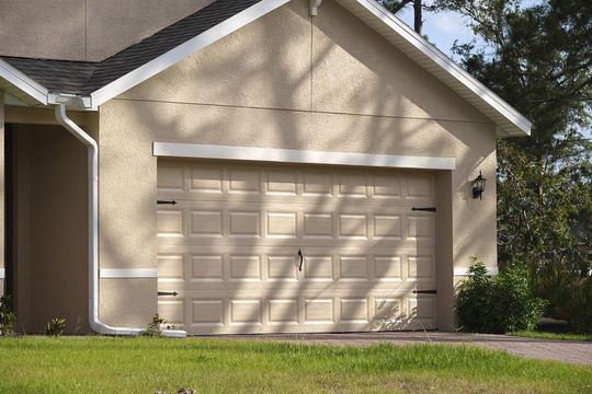 A beige garage door is sitting in front of a house.