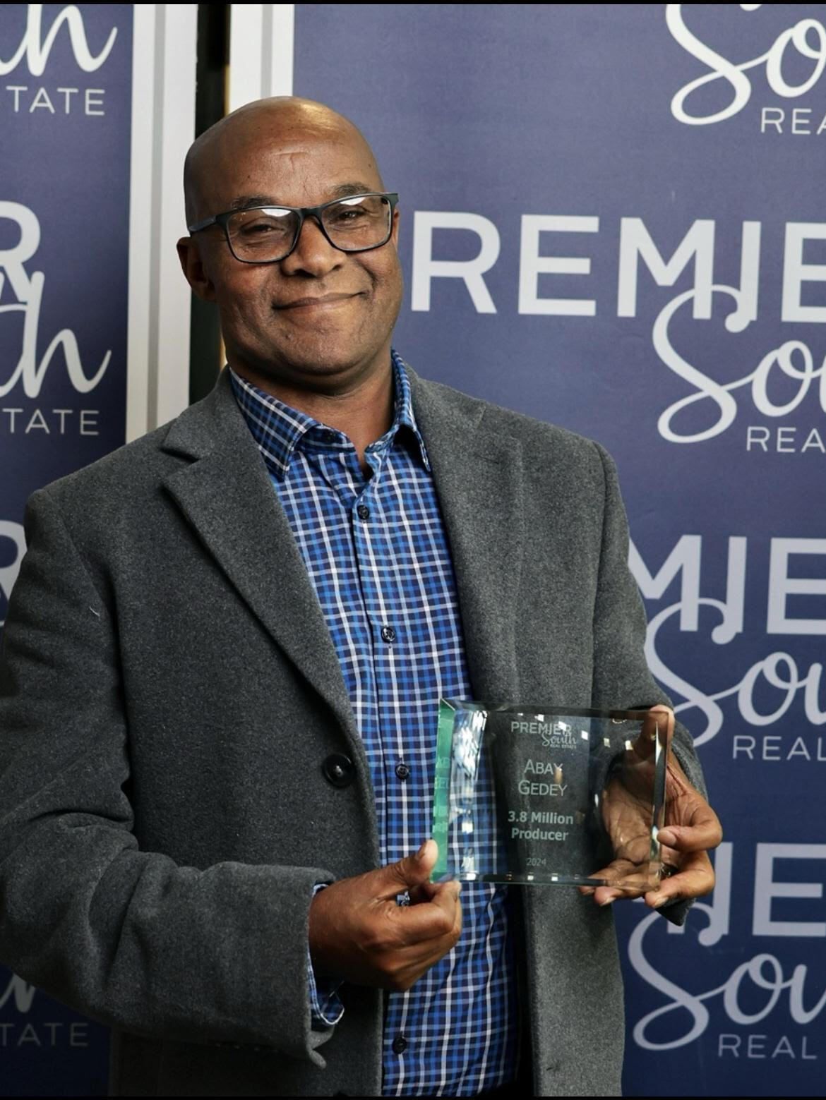 A man in a suit is holding a trophy in front of a sign that says remie