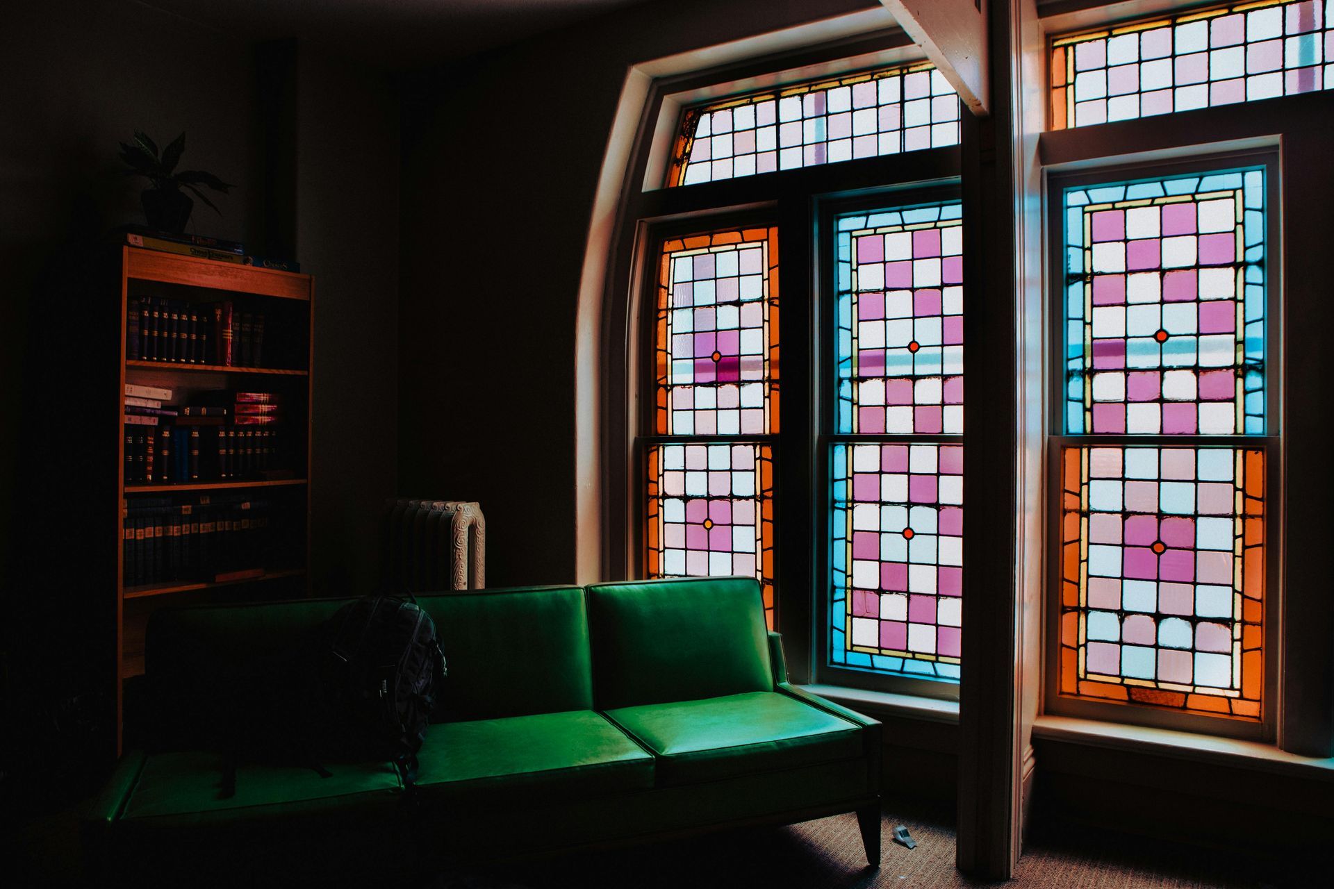 A living room with a green couch and stained glass windows.