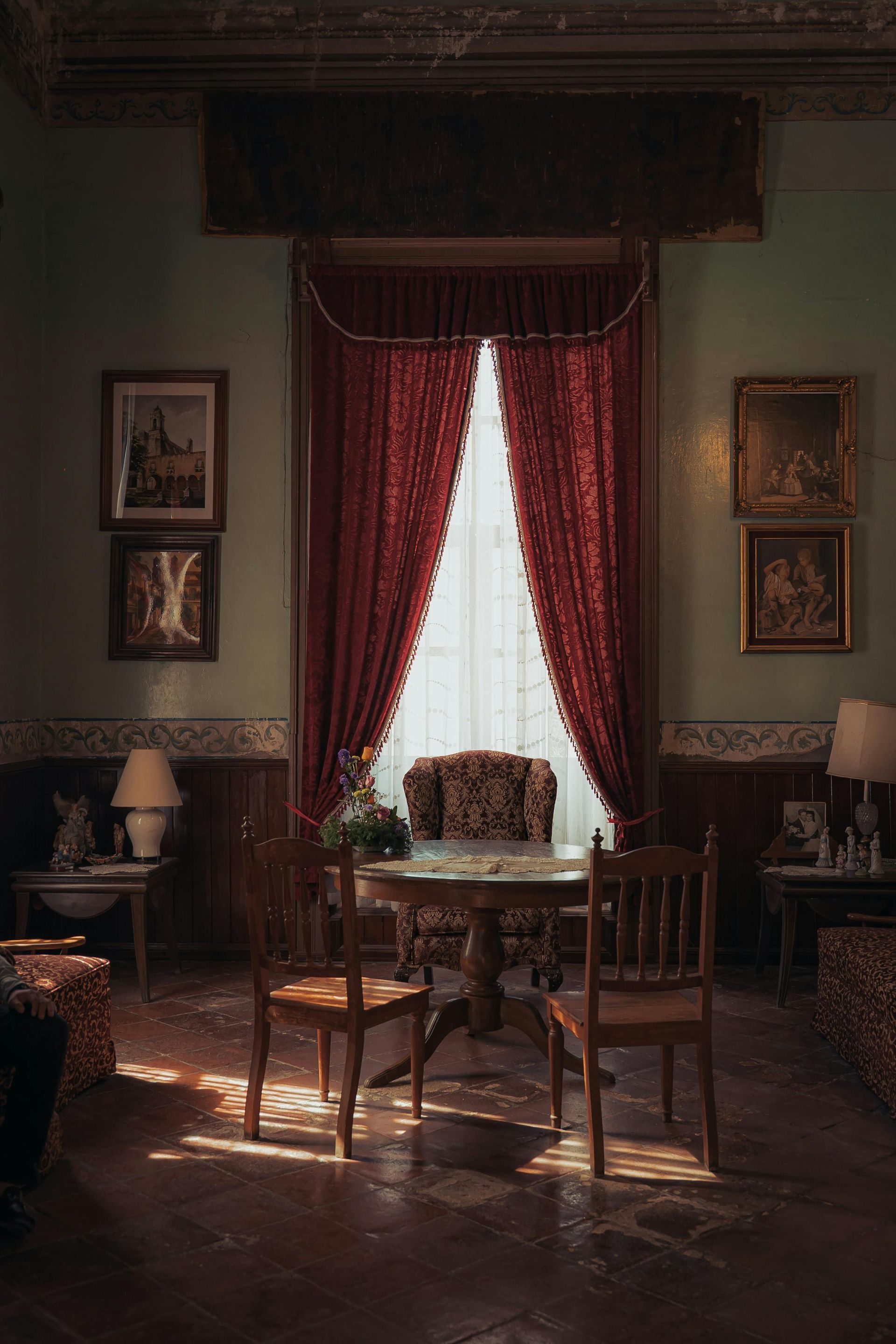 A living room with a table and chairs in front of a window.