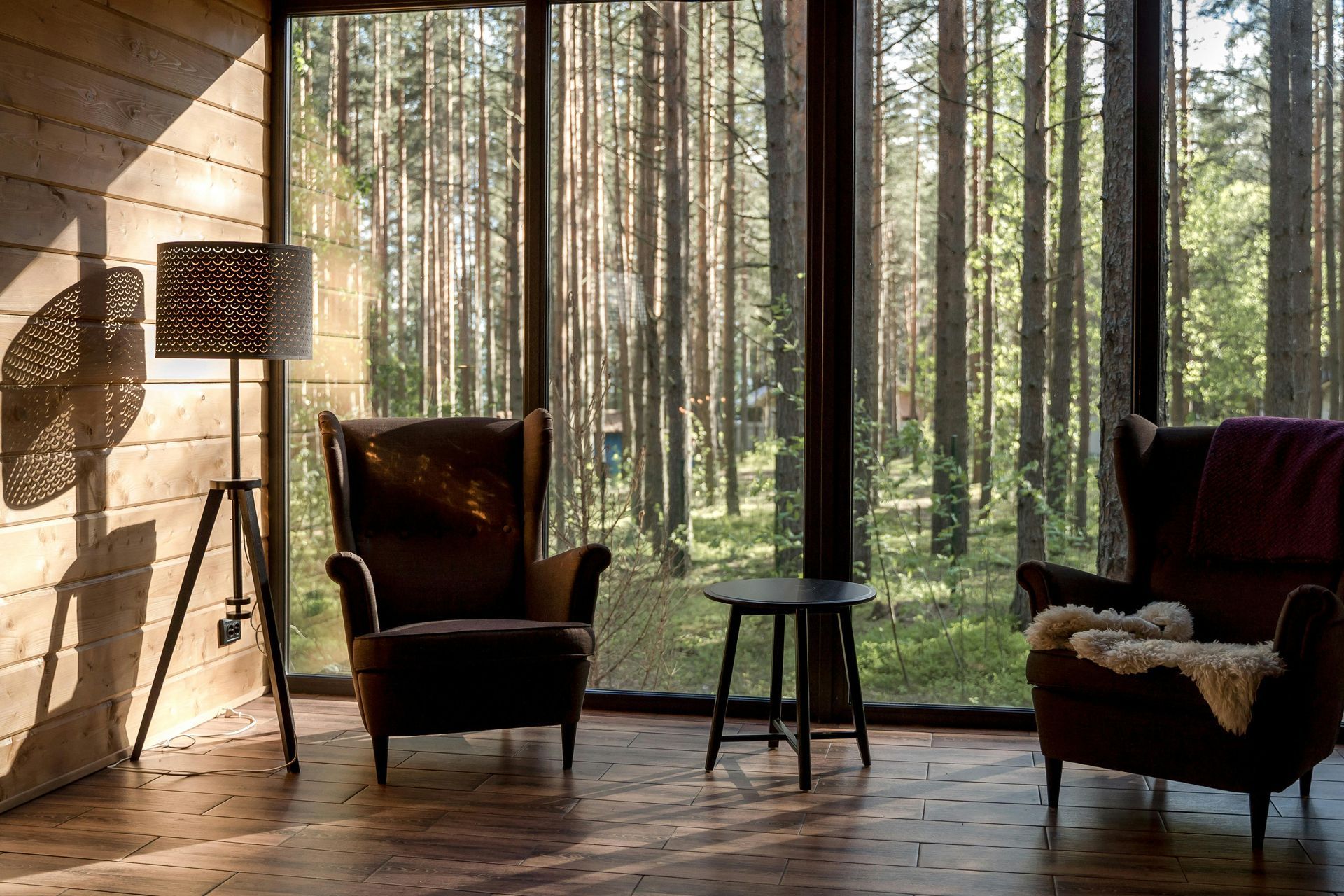 A living room with two chairs and a couch with a view of a forest.
