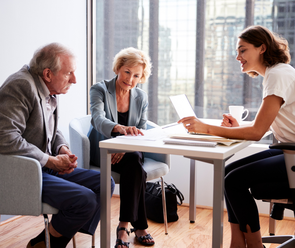 A woman is sitting at a table talking to two men
