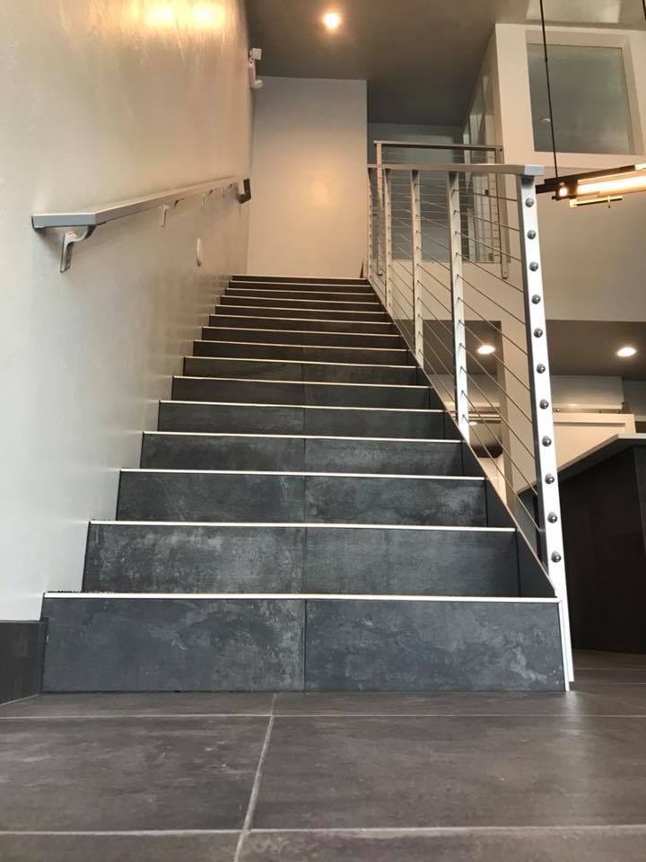 A set of stairs leading up to a second floor with a stainless steel railing.