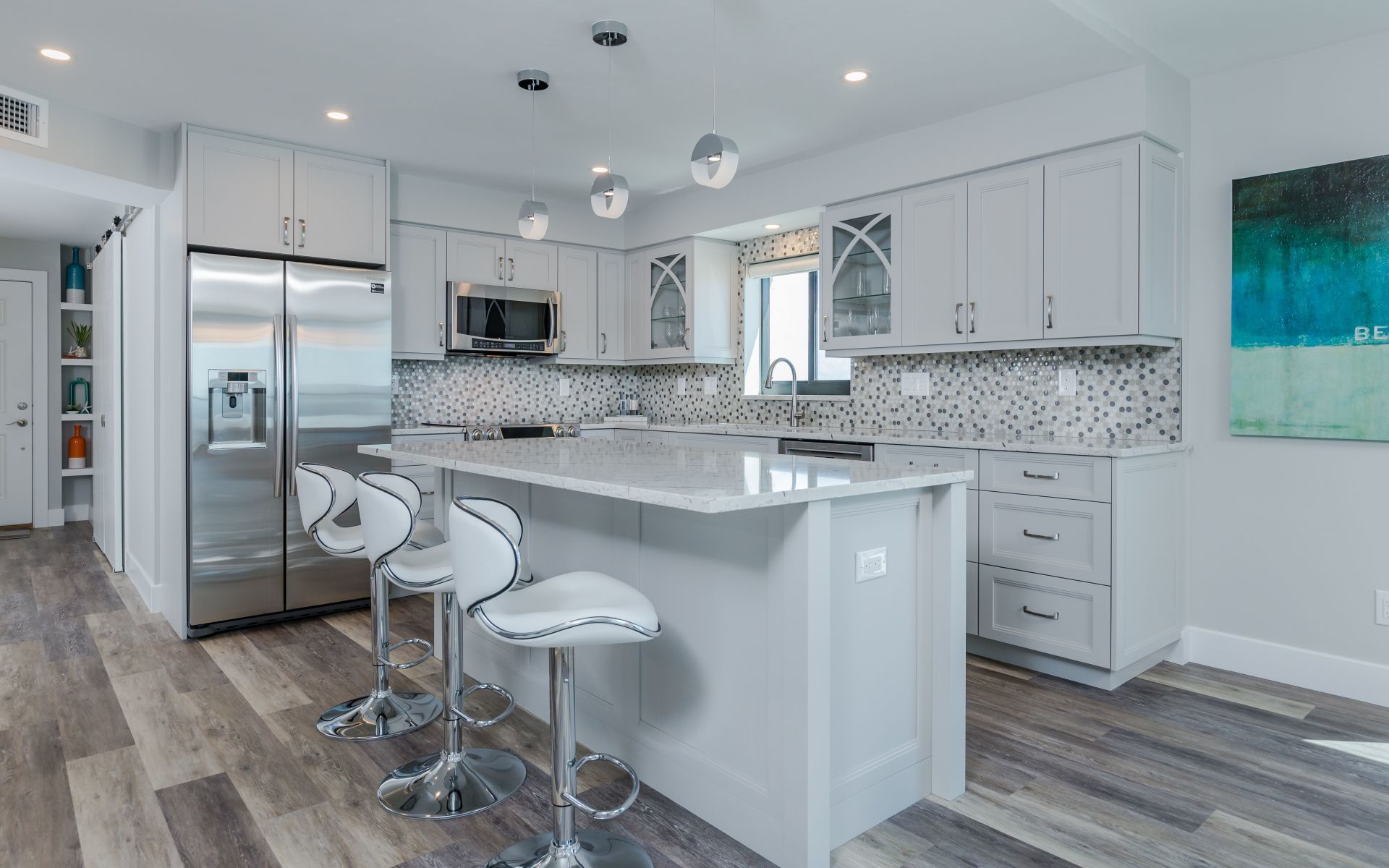 A kitchen with white cabinets , stainless steel appliances and a large island.