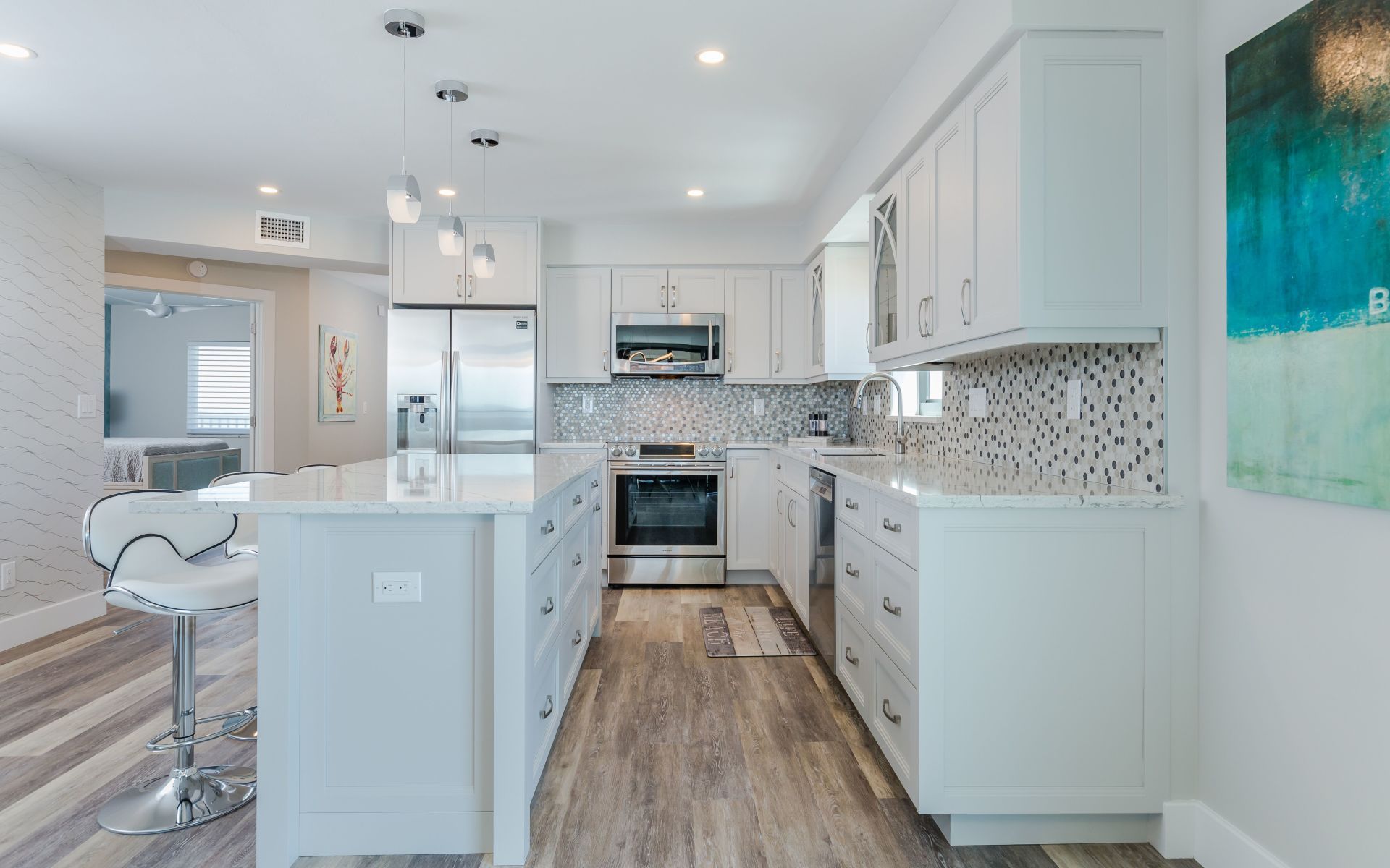 A kitchen with white cabinets , stainless steel appliances , and a large island.