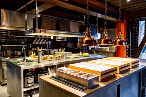 Modern commercial kitchen with stainless steel surfaces and open layout in a restaurant setting.