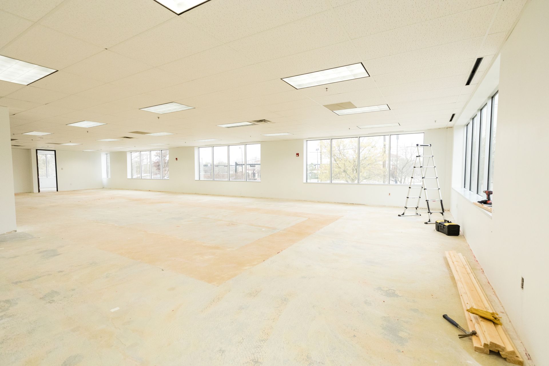 Inside of an empty recently-constructed office building with materials and ladder.