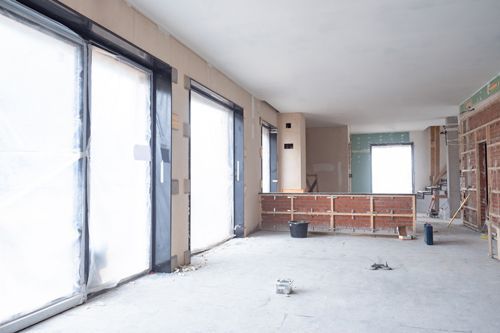 Office remodeling contractors renovating interior with exposed walls and plastic-covered windows Office remodeling contractors renovating interior with exposed walls and plastic-covered windows