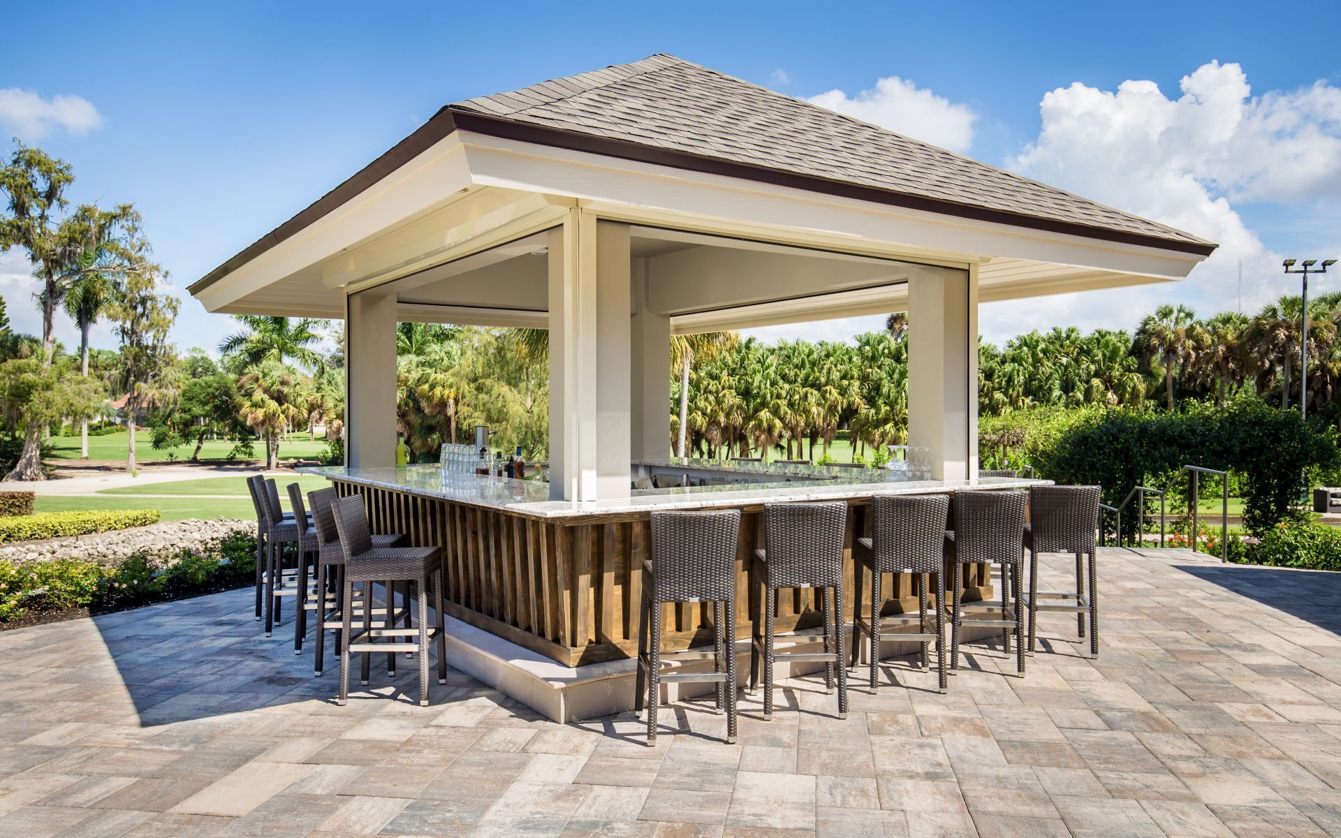 A large white building with a bar and chairs in front of a golf course.
