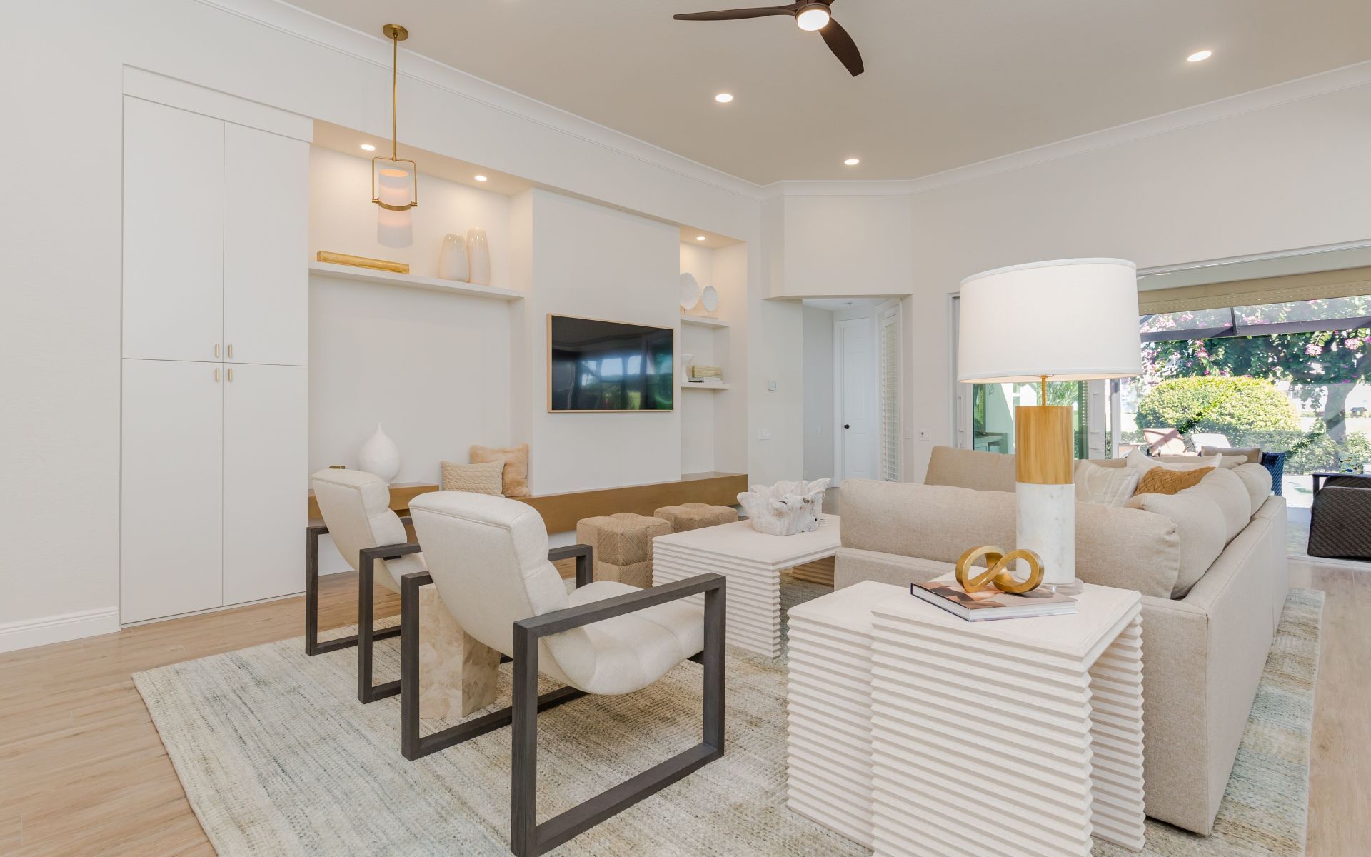 A living room with a couch , chairs , tables and a ceiling fan.