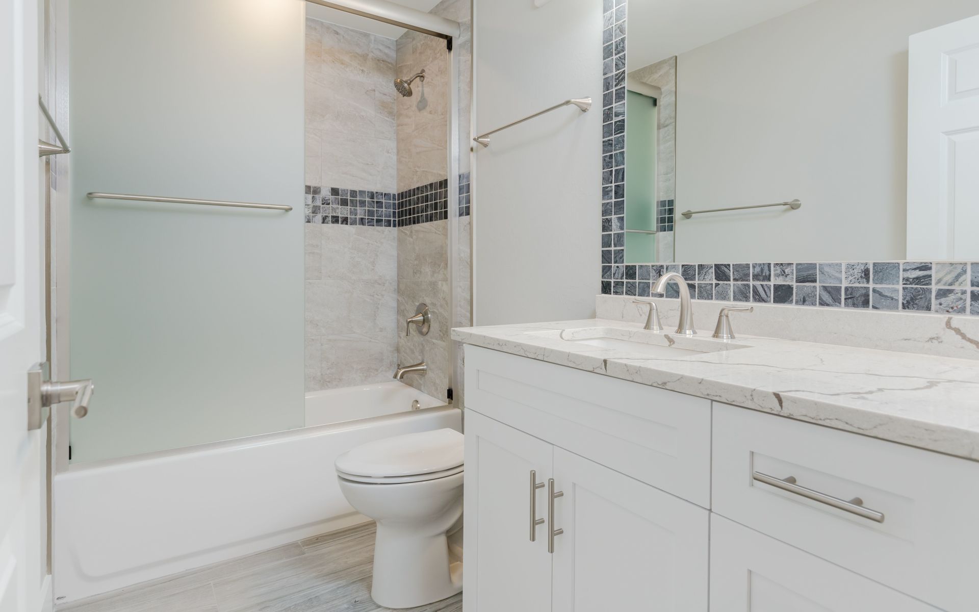 A bathroom with a toilet , sink , tub and mirror.