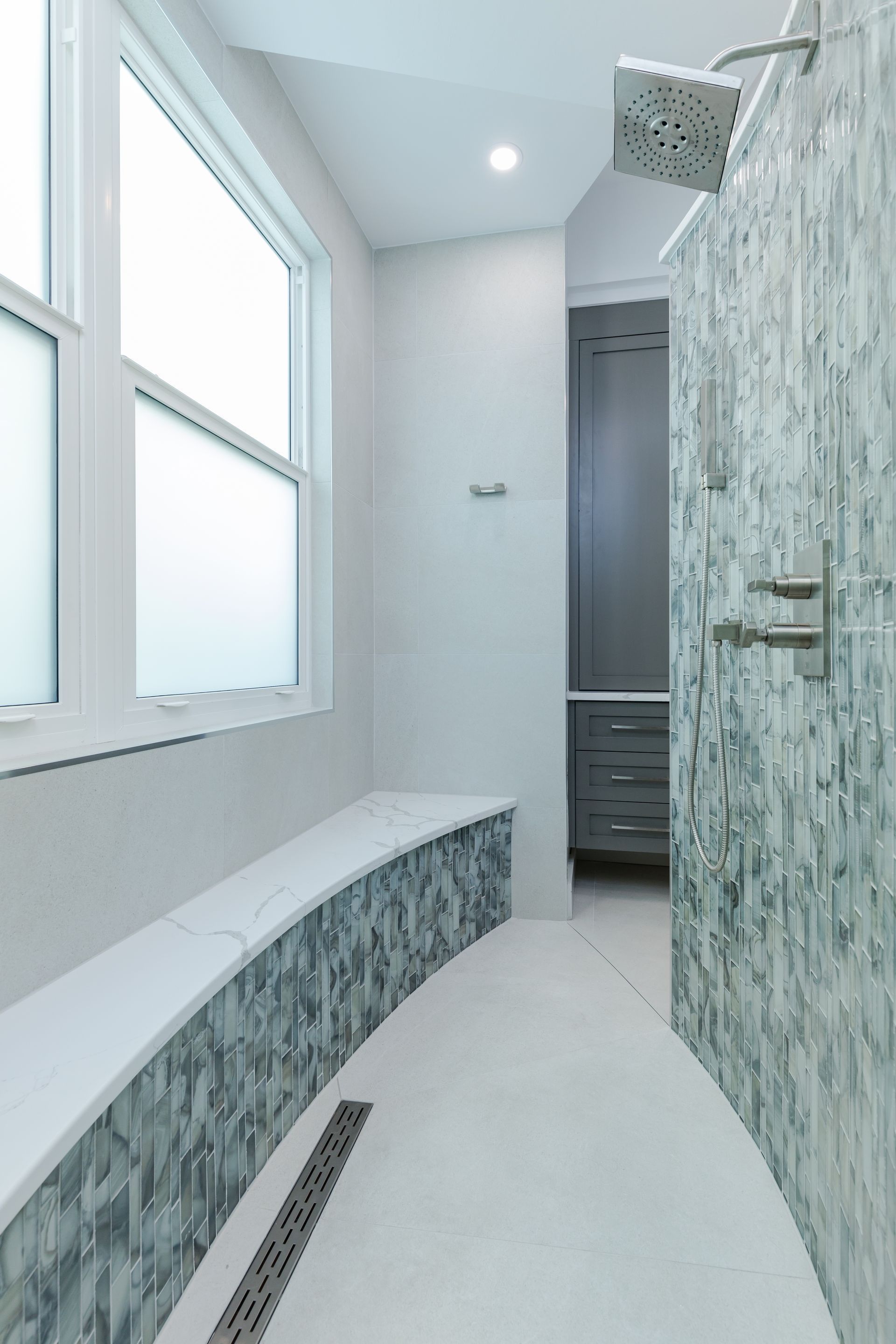 A bathroom with a walk in shower and a bench.