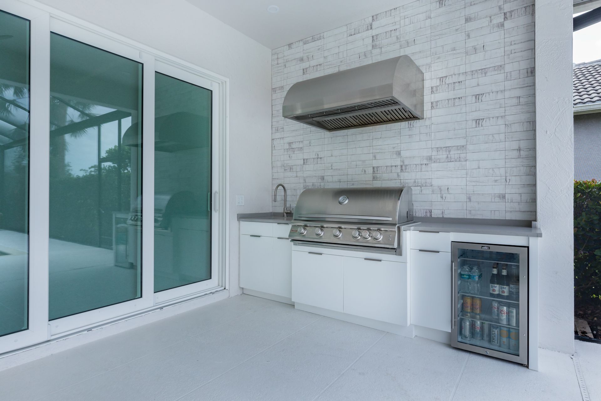 A patio with a grill , refrigerator and sliding glass doors.