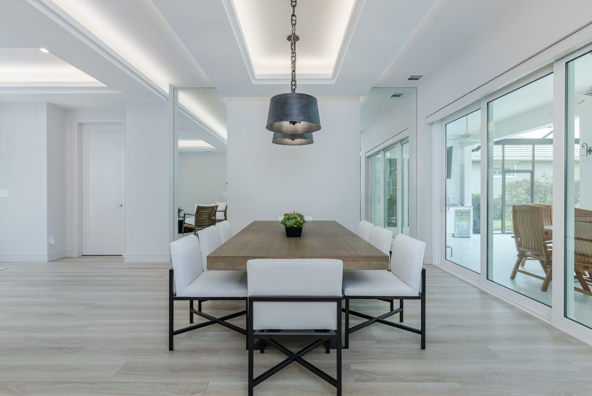 A dining room with a long wooden table and white chairs