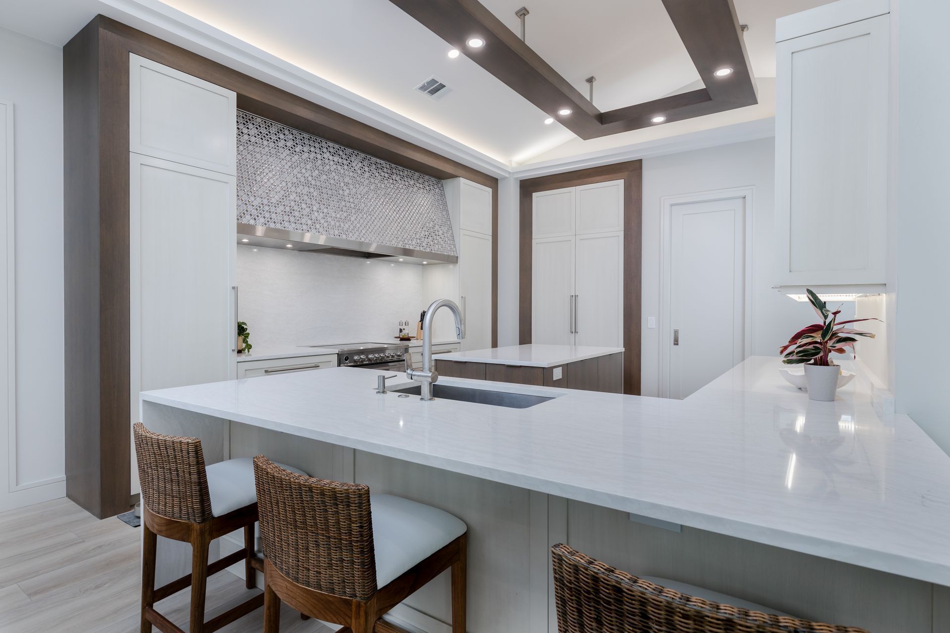 A kitchen with a large island and two wicker chairs.