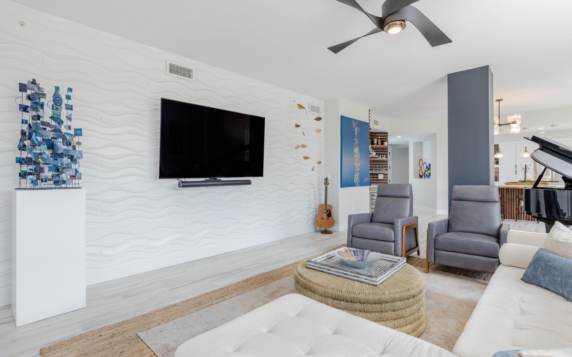 A living room with a couch , chairs , and a flat screen tv.