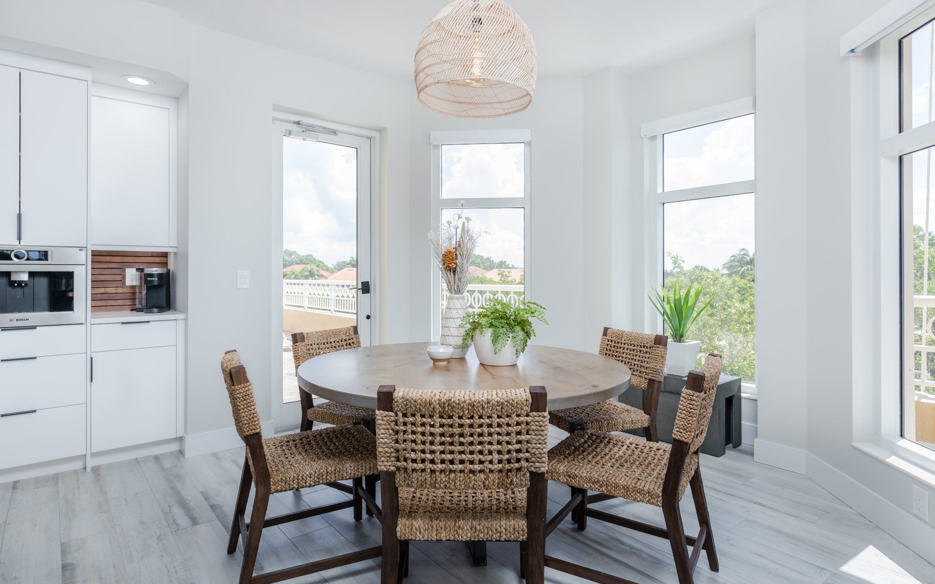 A dining room with a round table and wicker chairs.