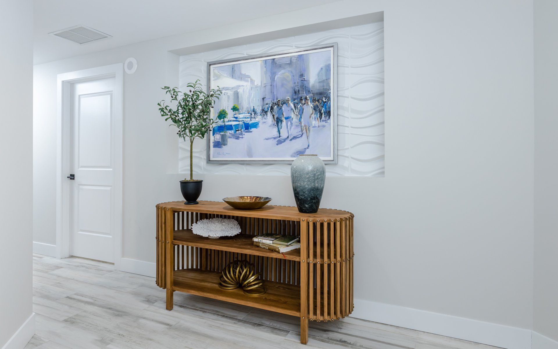 A hallway with a wooden table and a painting on the wall.