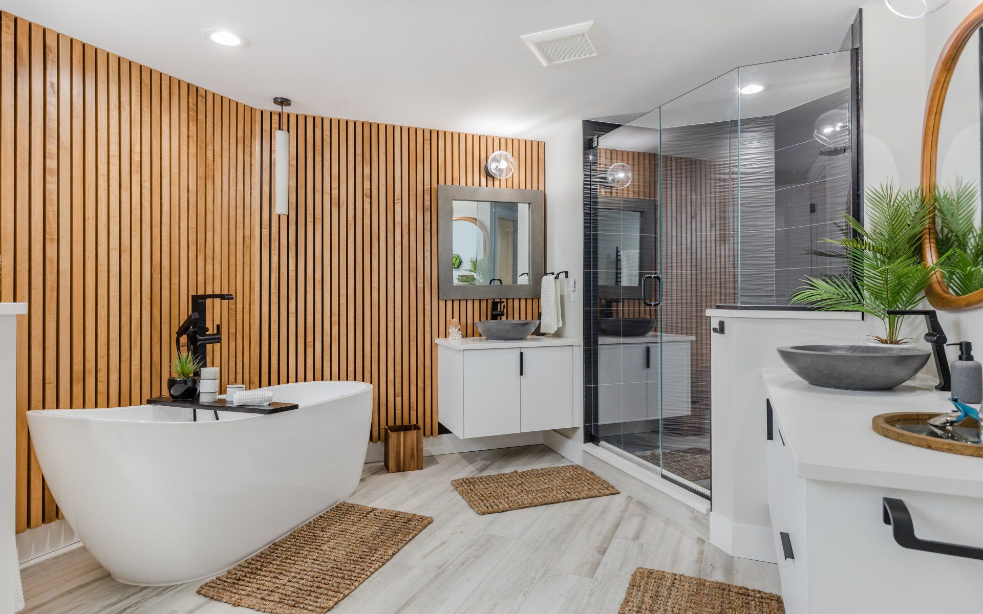 A bathroom with a bathtub , sinks , mirrors and a walk in shower.