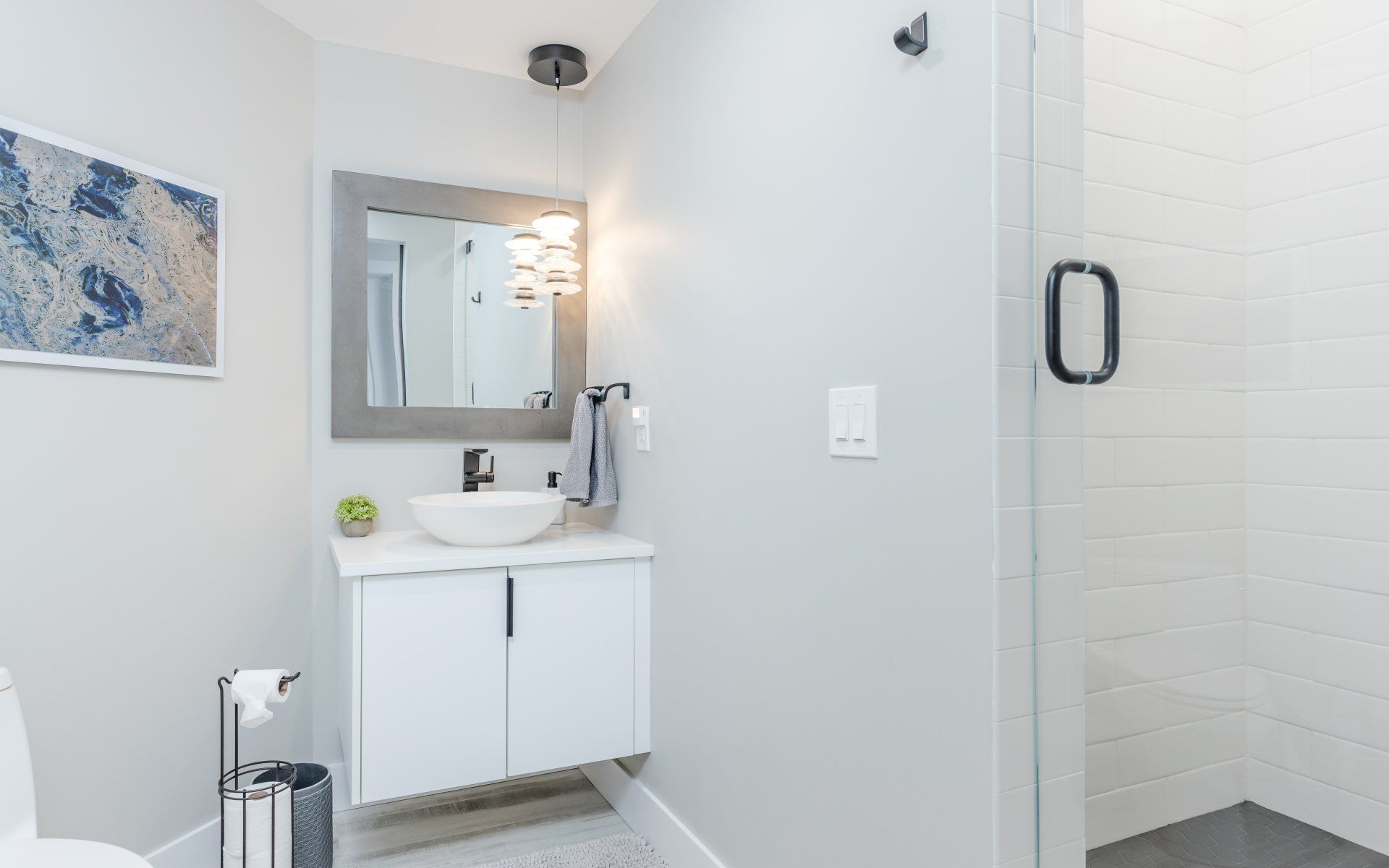 A bathroom with a sink , toilet , mirror and walk in shower.