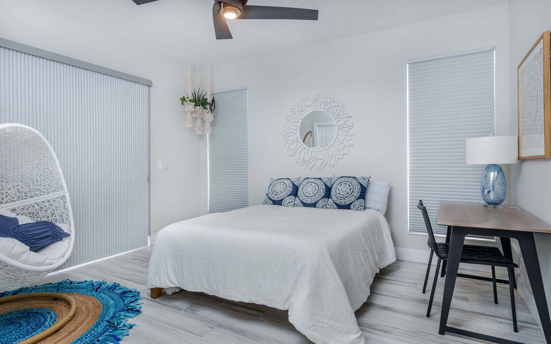 A bedroom with a bed , desk , chairs and a ceiling fan.