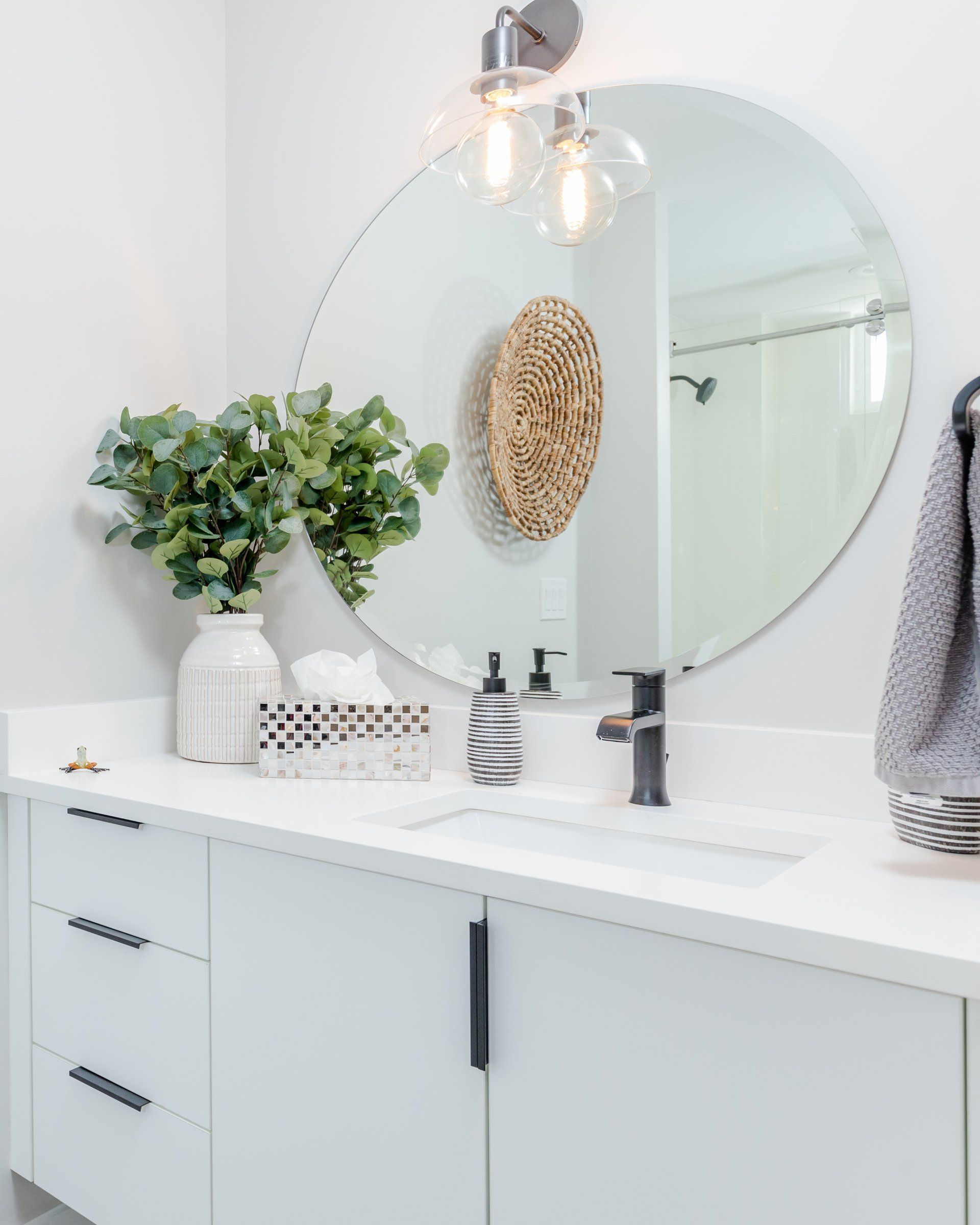 A bathroom with a sink and a round mirror.
