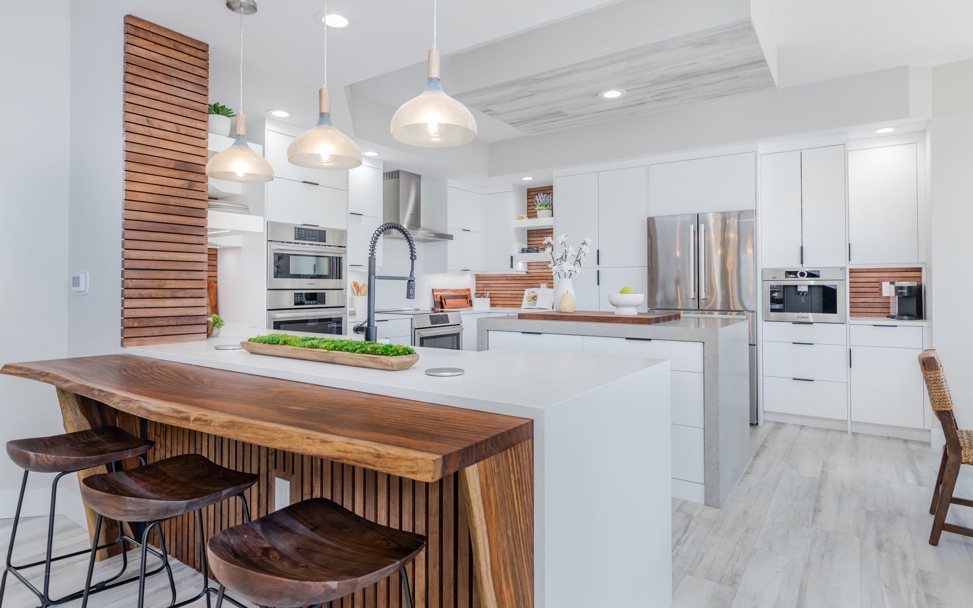 A kitchen with white cabinets , stainless steel appliances , a wooden island and stools.