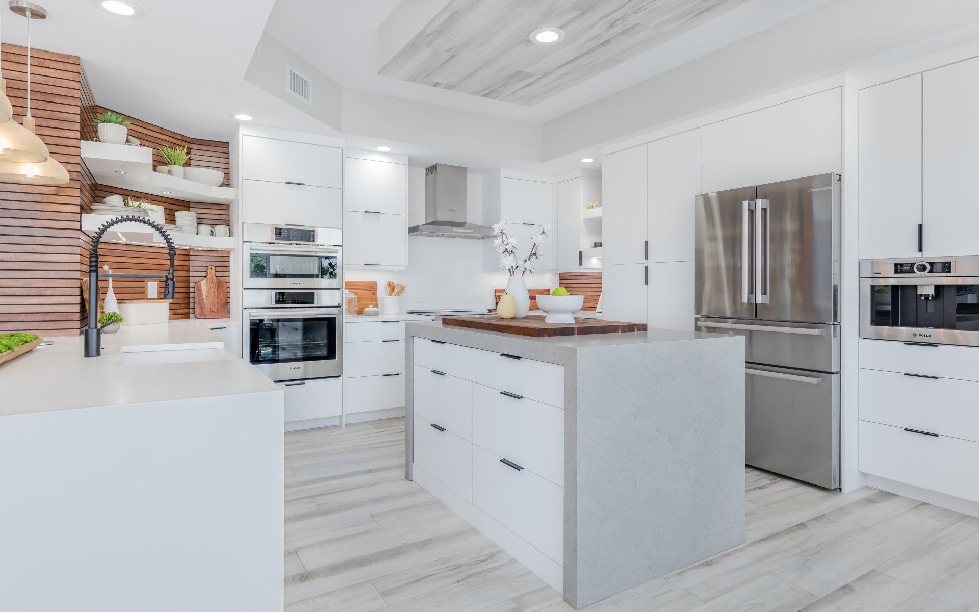 A kitchen with white cabinets , stainless steel appliances and a large island.