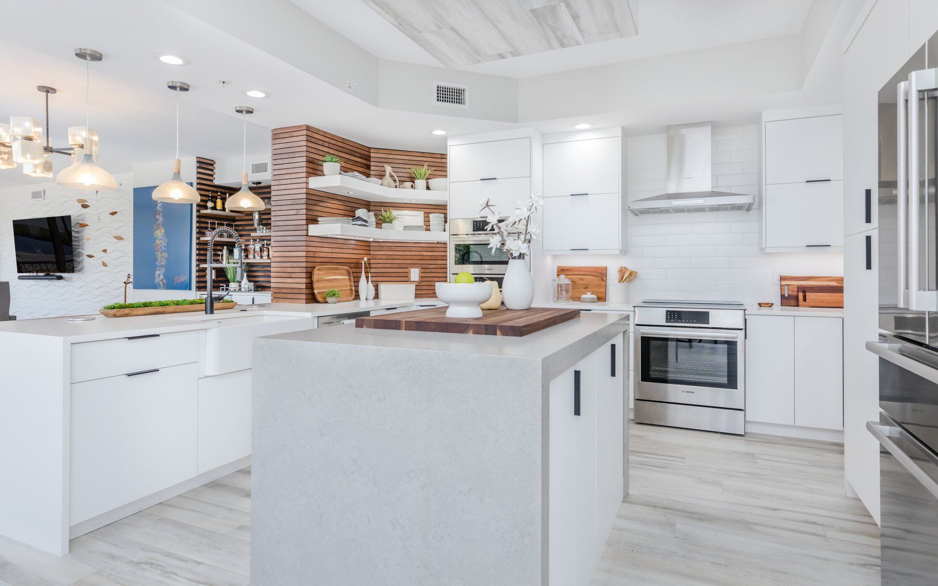 A kitchen with white cabinets and stainless steel appliances and a large island in the middle.