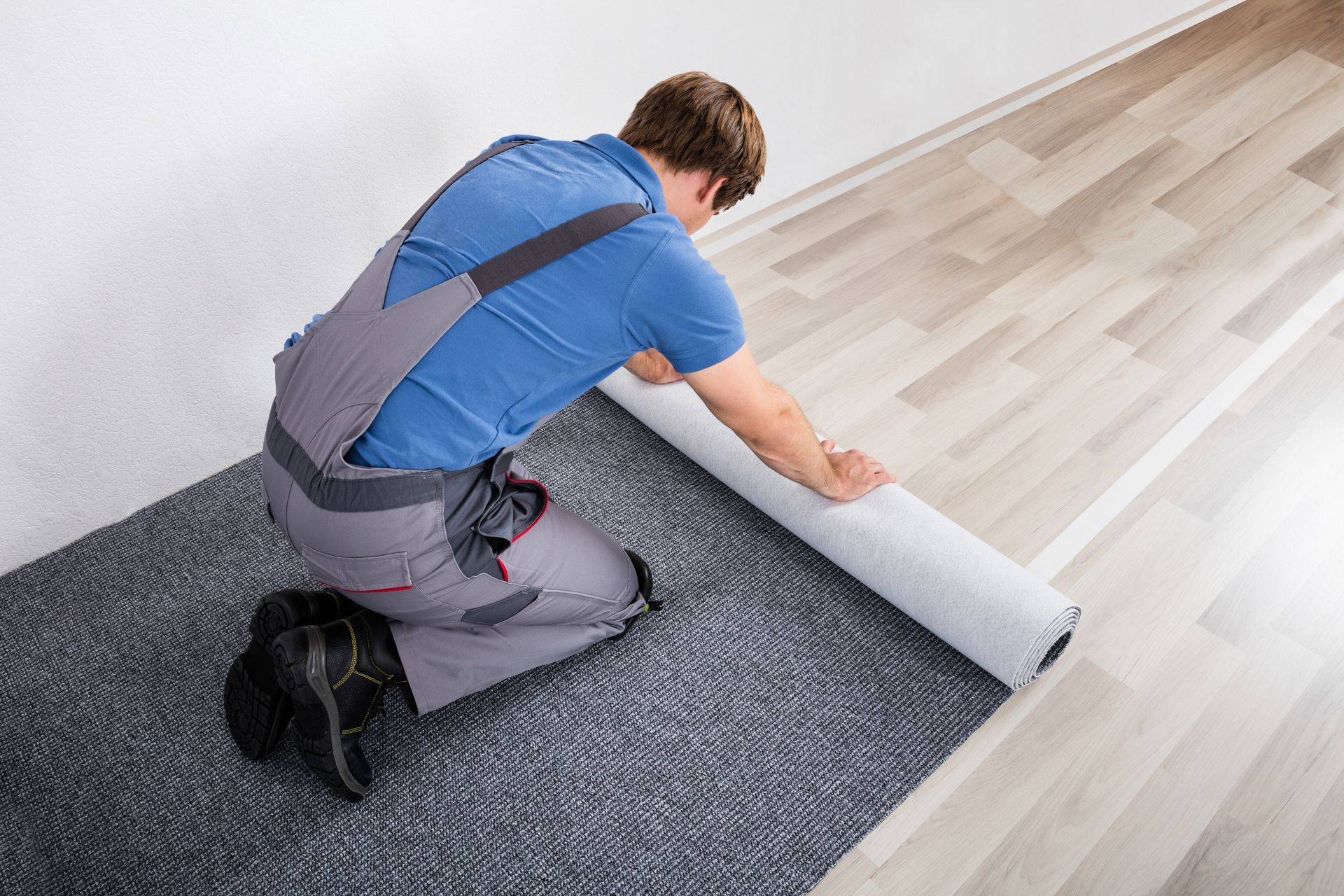 Male handyman places carpet on wooden floor, representing commercial remodeling contractor services.