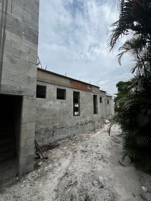 A brick building under construction with a palm tree in the background.