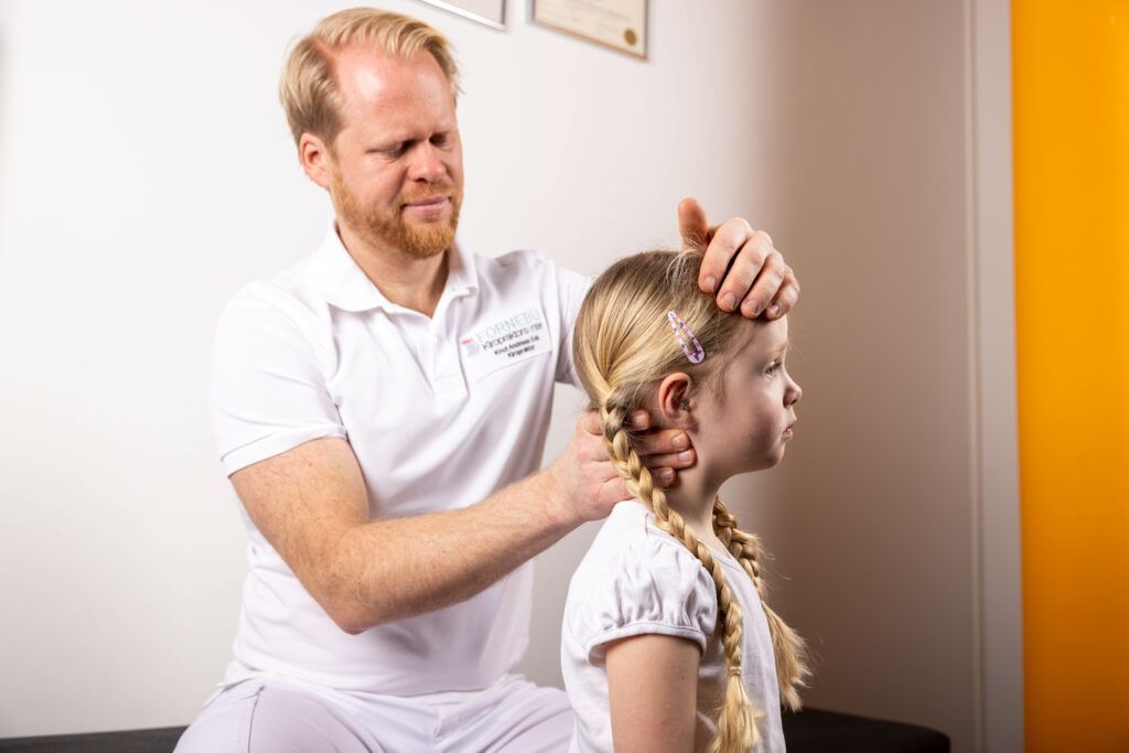 Mann undersøker en ung persons nakke og hode på et kontor.